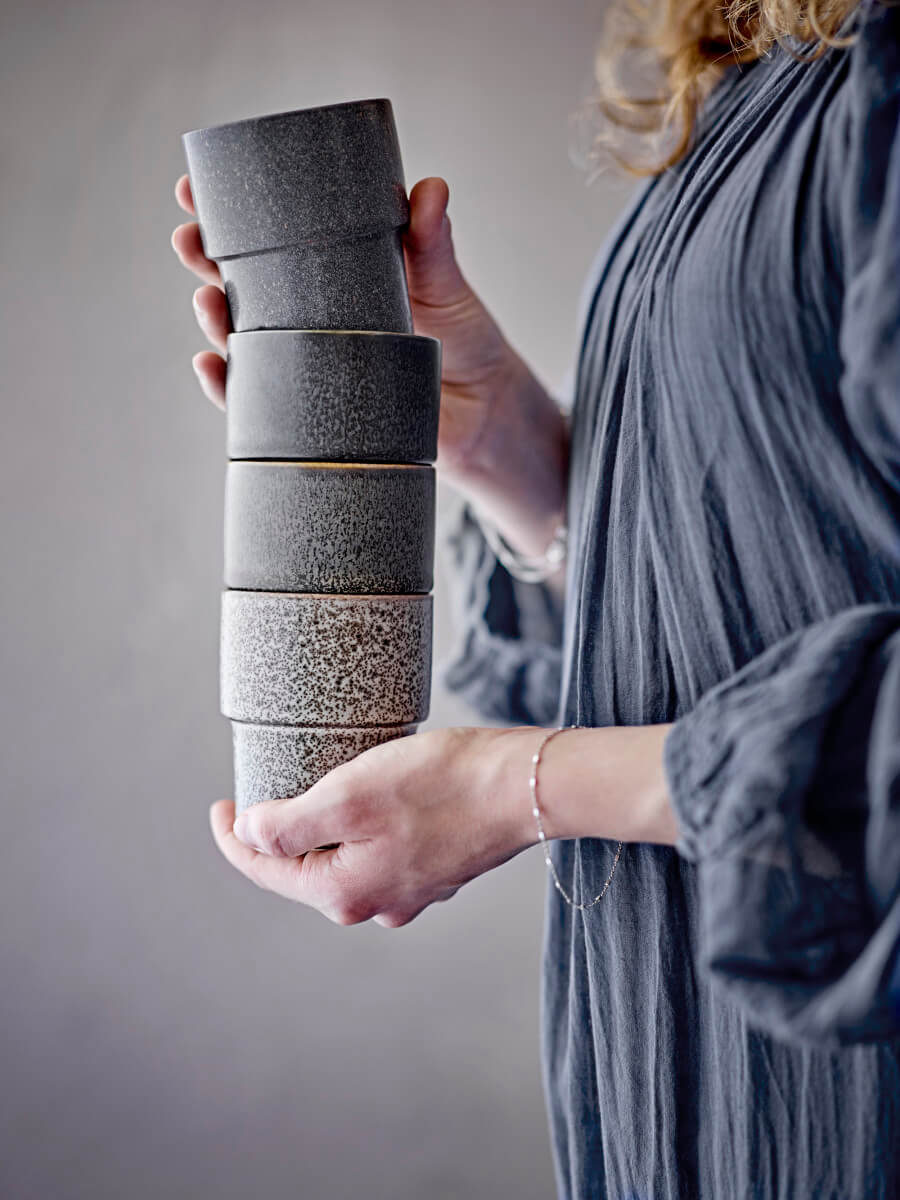 Handcrafted ceramic cups in earthy tones held in a natural lifestyle setting