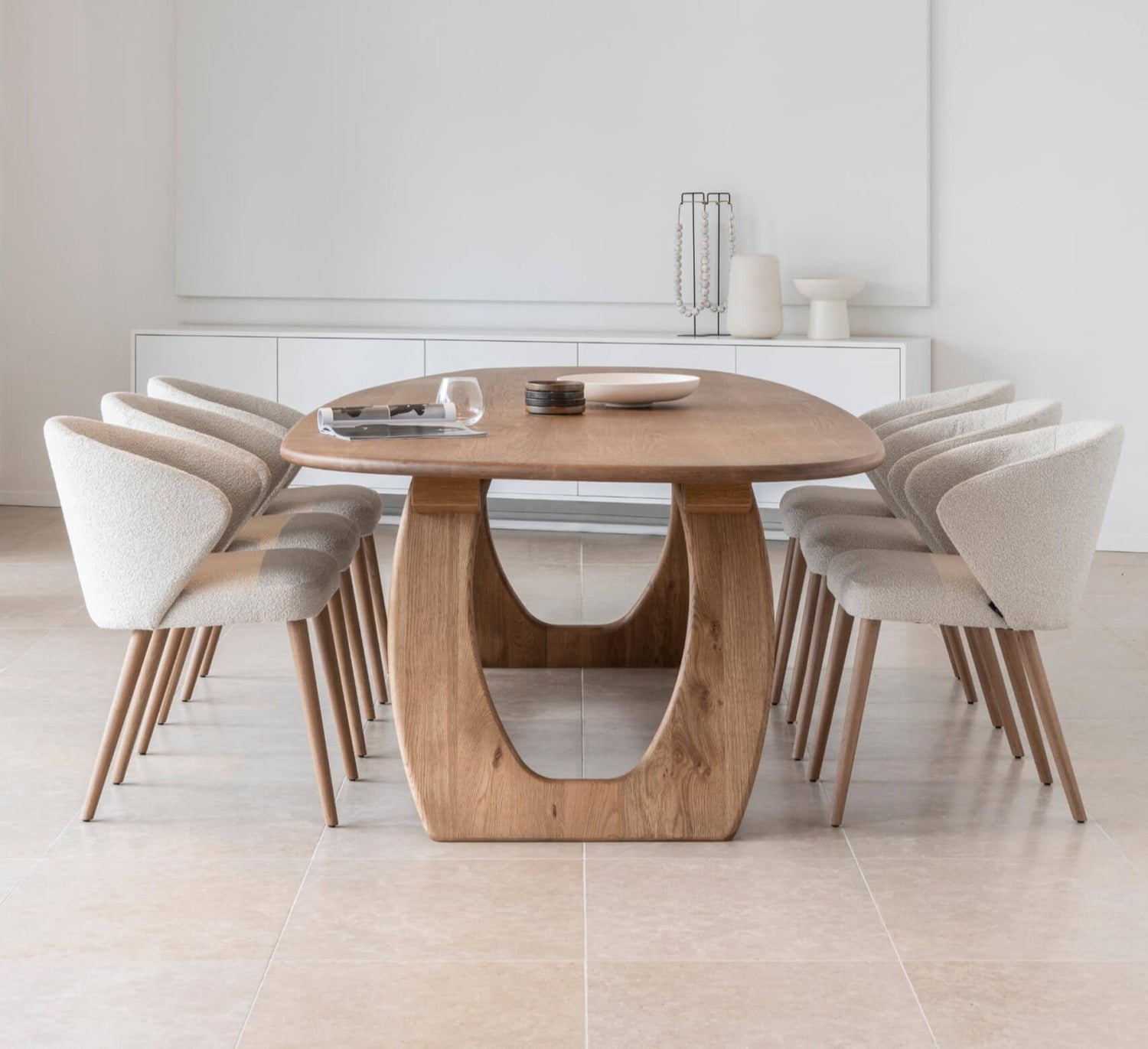 Minimalist dining setting featuring a round wooden table and upholstered chairs by MOBITEC