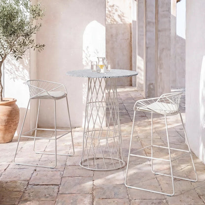 שולחן בר Bolina ושני כסאות בר Bolina בלבן, בחצר לבנה עם קשתות ועץ זית