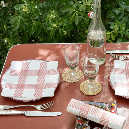 מפיות Rustic Rouge מבית Françoise Paviot במשבצות אדומות על שולחן בגינה